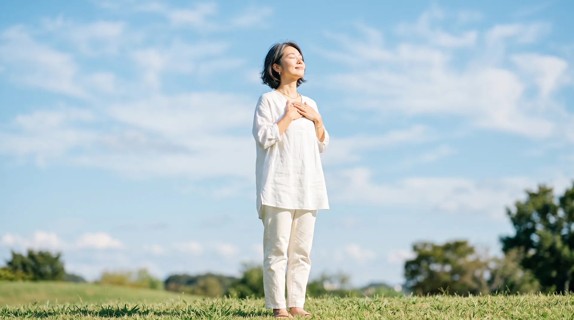 青空の下で深呼吸をする女性